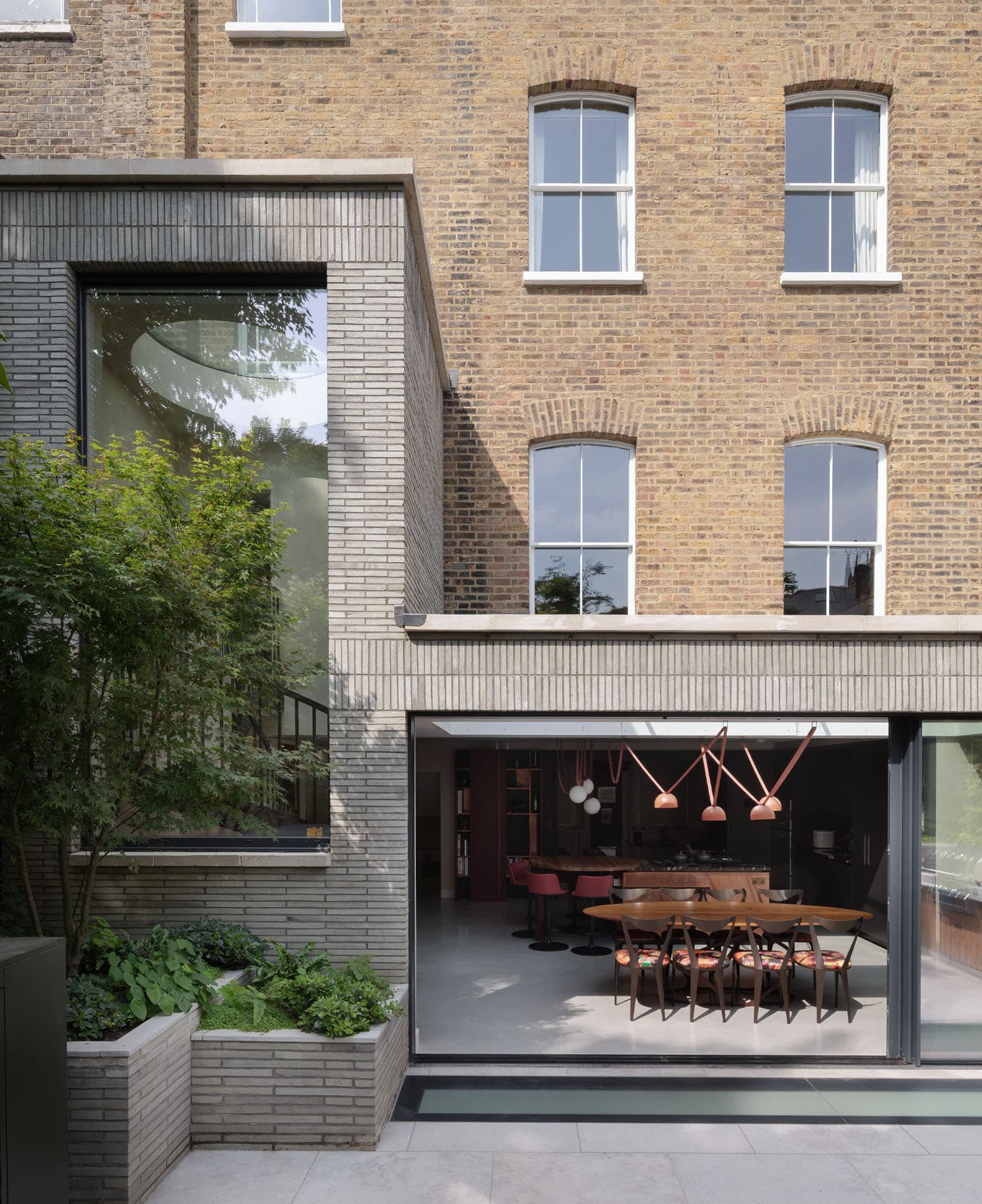 Rear extension of a London brick terrace house with a glass-box dining room